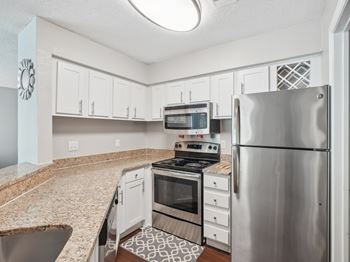 A kitchen with a stainless steel refrigerator, oven, and microwave